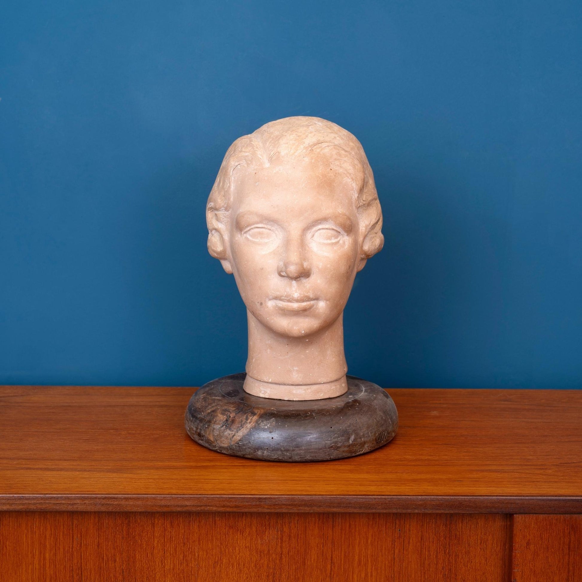 Scultura in terracotta raffigurante la testa di una donna, con base in legno e risalente ai primi del ‘900.