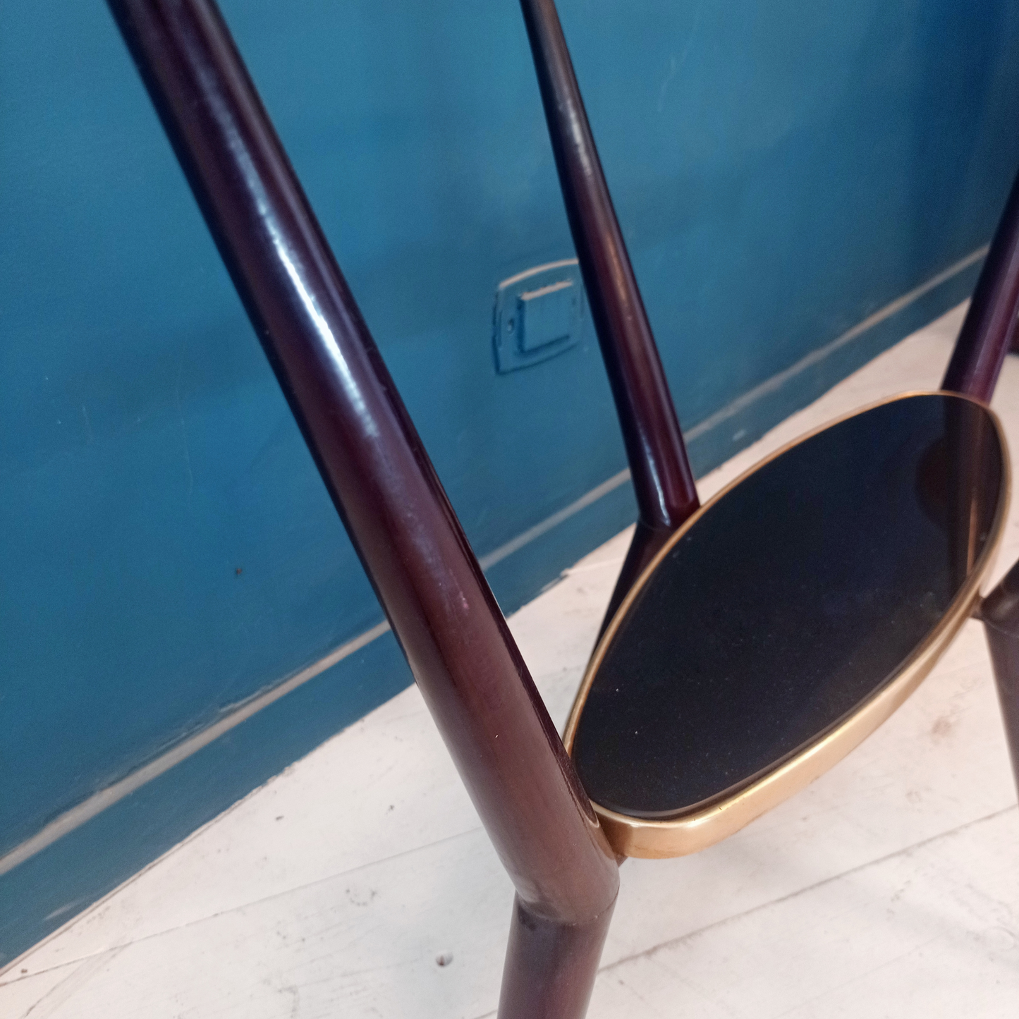 Dettaglio struttura tavolino da caffè vintage ovale con due ripiani in vetro, gambe in legno e borchie in ottone risalente agli anni '50. 