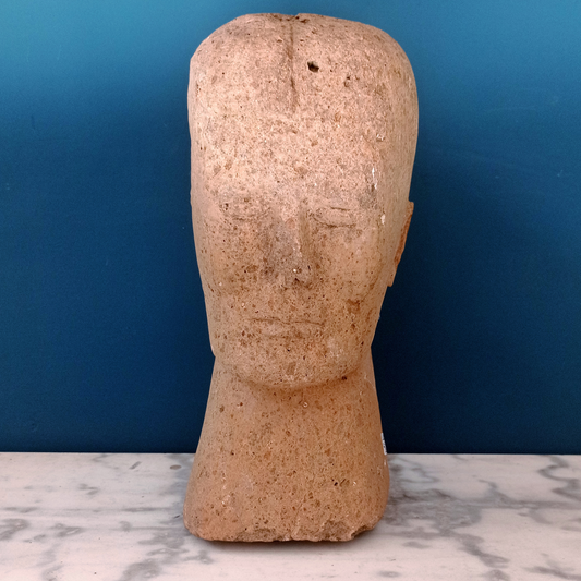 Scultura in peperino rosa raffigurante una testa di ispirazione etrusca, prodotta in Italia nella prima metà del '900.